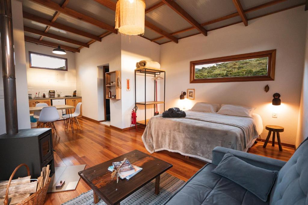 a bedroom with a bed and a living room at Vale Mandaçaia in Urubici
