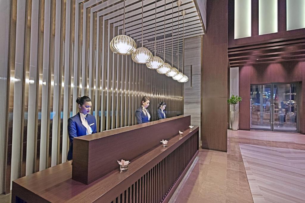 多哈White Square Curve Hotel & Suites的两个人站在大厅的柜台上