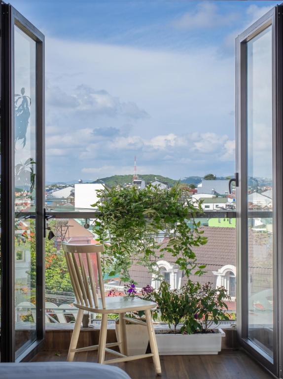 a chair on a balcony with a view of a city at Tasme Dalat Signature in Da Lat
