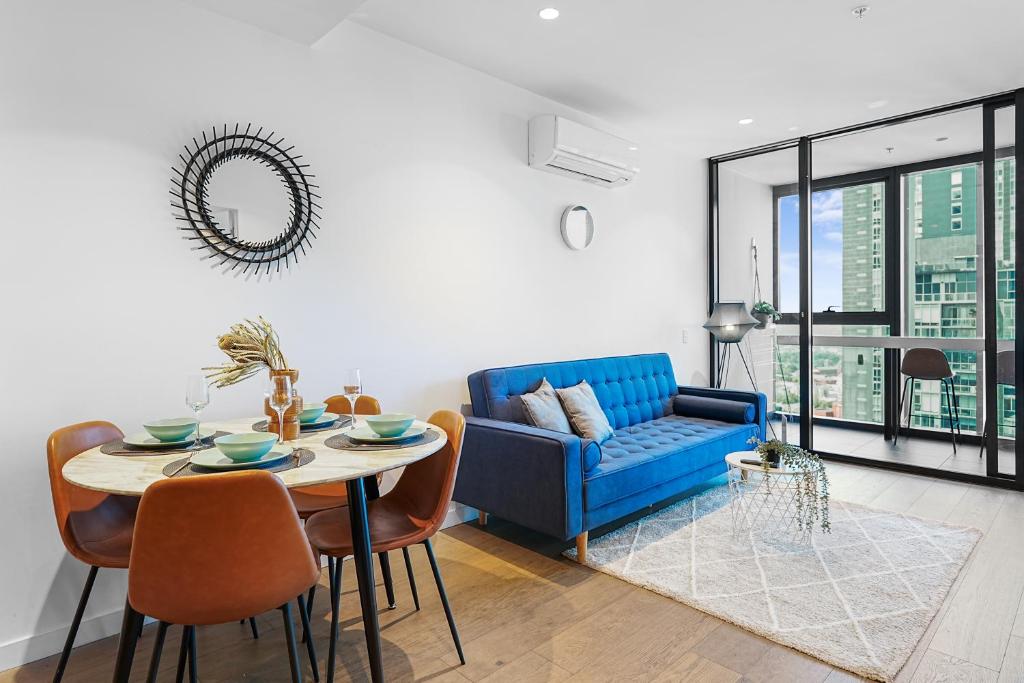 メルボルンにあるElegant High Rise 2 Bed Apt near Melb CBD RMITの青いソファとテーブルのあるリビングルーム
