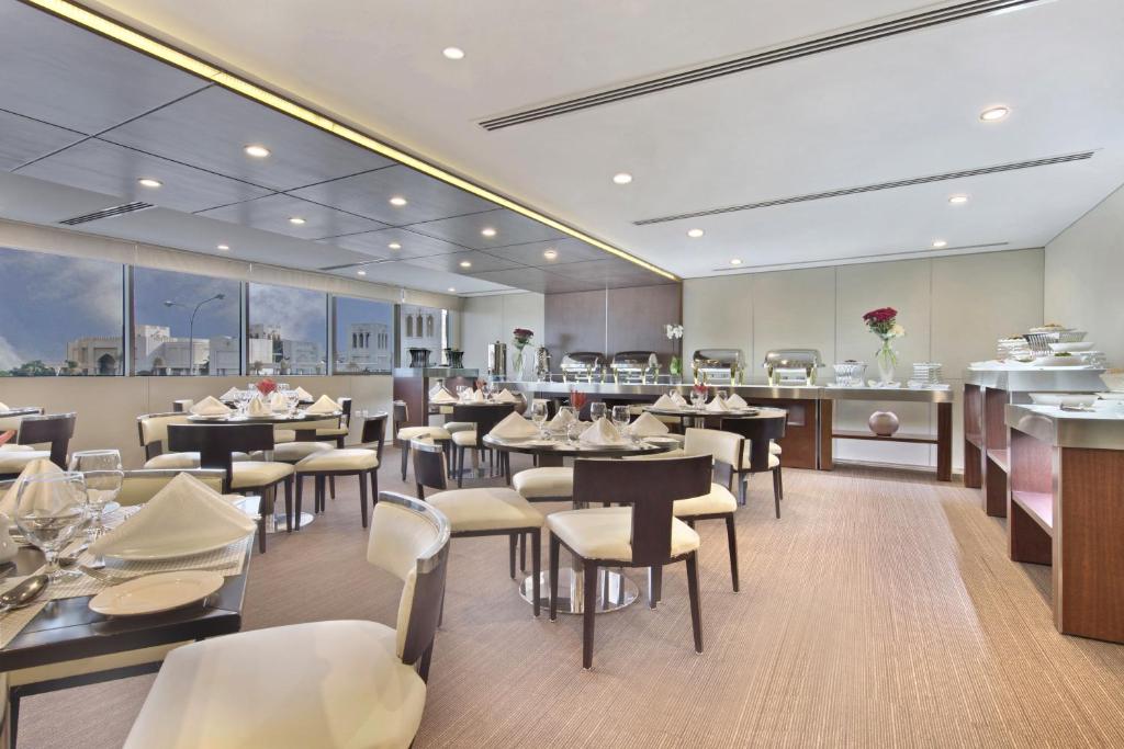 多哈White Square Curve Hotel & Suites的有桌椅和酒吧的餐厅