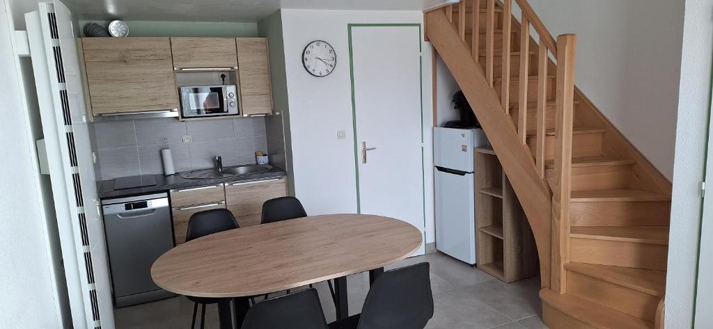 a small kitchen with a wooden table and a staircase at Domaine in Saint-Hilaire-de-Riez