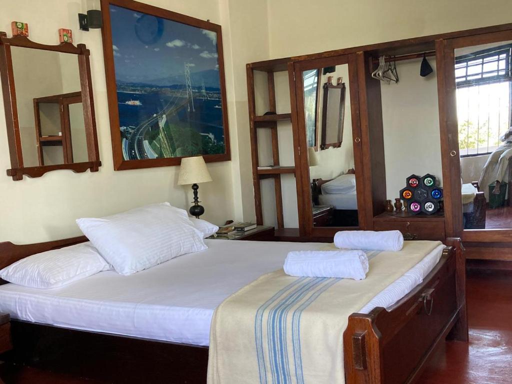 a bedroom with a large bed with two mirrors at Woodlands Homestay - Kandy in Teldeniya