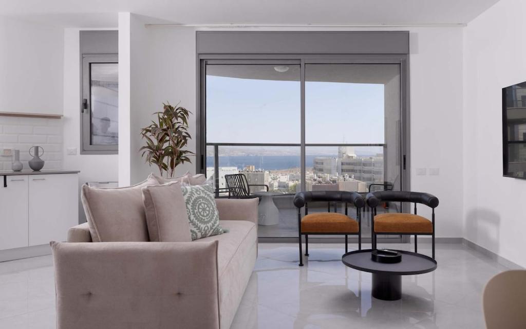 a living room with a couch and chairs and a table at דירת משפחה מודרנית עם נוף לים in Eilat