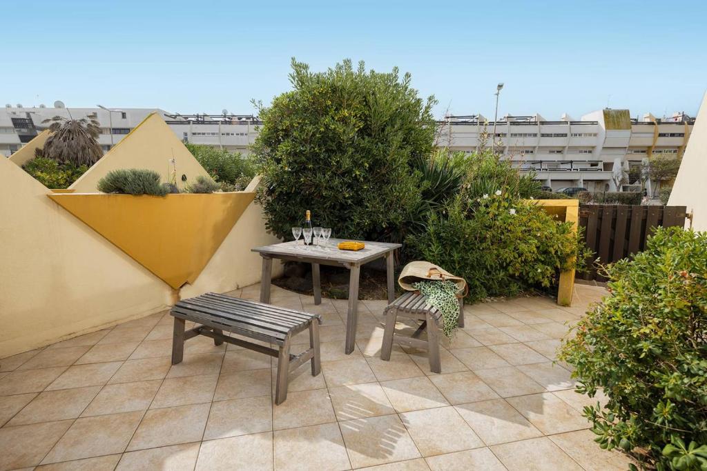 un petit patio avec une table et un banc dans l'établissement STUDIO MAXXX - Héliopolis E85 Luxe 4 personnes, au Cap d'Agde