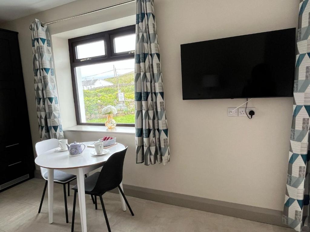 a dining room with a white table and a window at Tigh Fitz Apartments - Inis Mór, Aran Island in Inis Mor