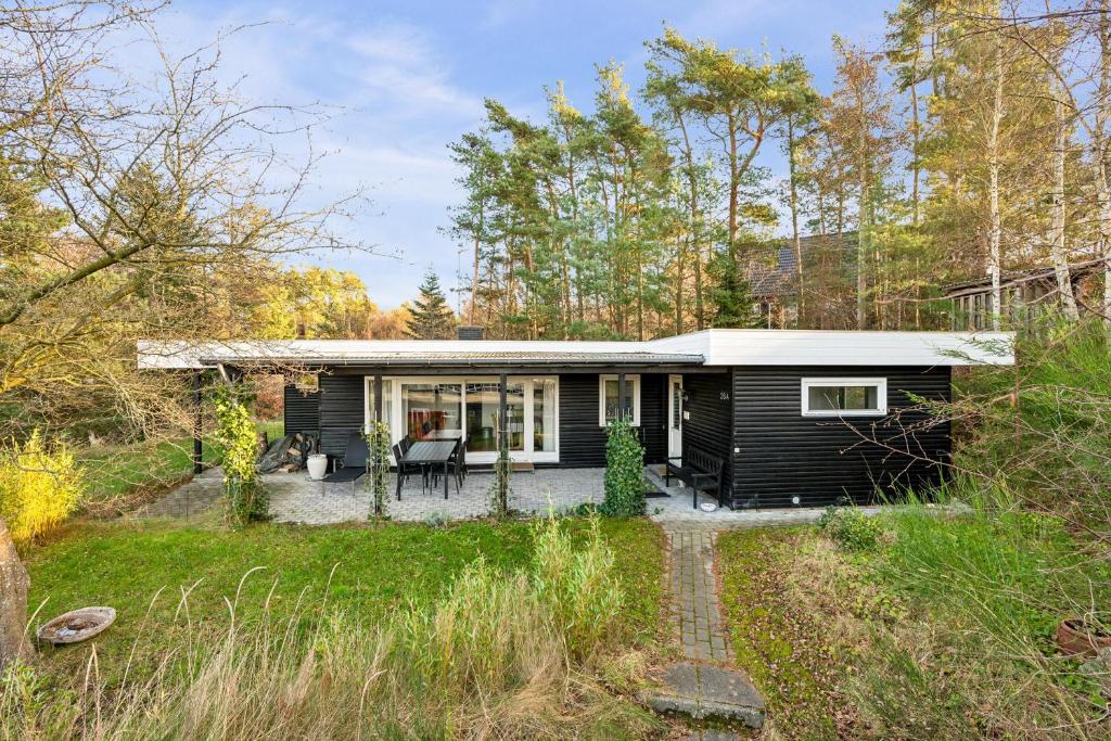 Une petite maison noire dans les bois dans l'établissement Cozy Nature Getaway Just Minutes From Ebeltoft And Top Attractions, à Ebeltoft