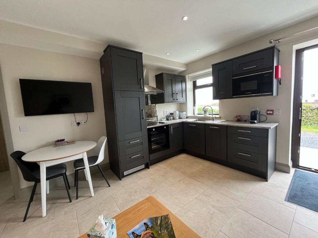 a kitchen with black cabinets and a table and a tv at Tigh Fitz Apartments - Inis Mór, Aran Island in Inis Mor