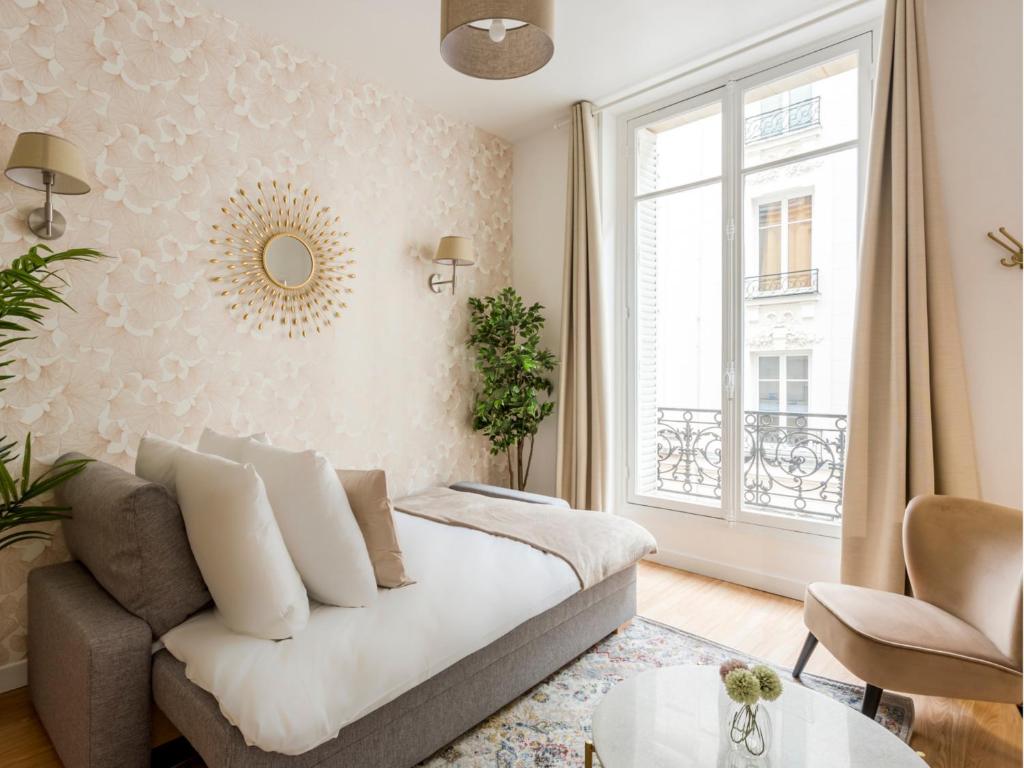 un salon avec un canapé et une fenêtre dans l'établissement Merveil - Family Suite - Marais - Martin IV, à Paris