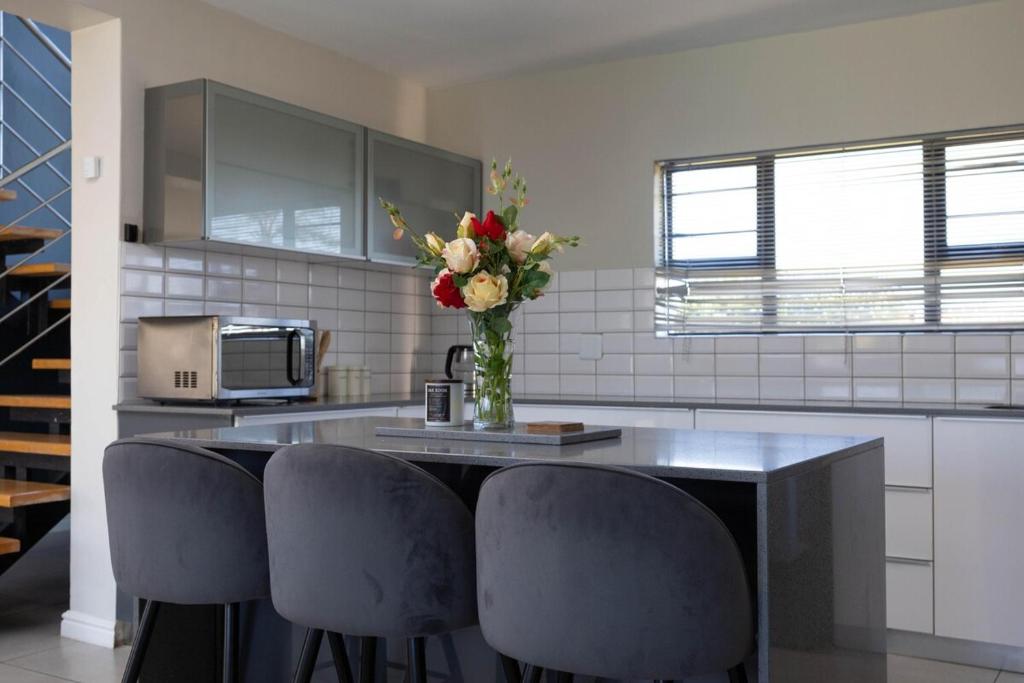 a kitchen with a counter with chairs and a vase of flowers at Bluewater Bay Escape in Gqeberha