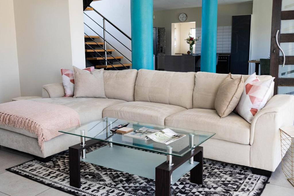 a living room with a white couch and a glass table at Bluewater Bay Escape in Gqeberha