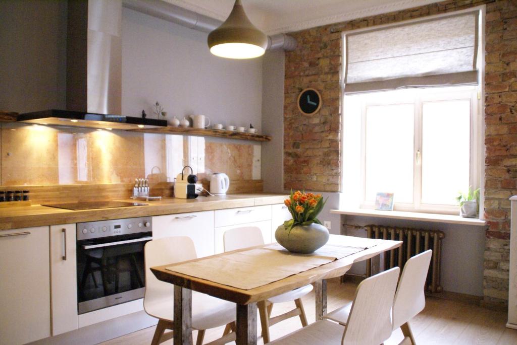 una cucina con tavolo in legno e sedie bianche di Art deco new apartment in the centre of Riga a Riga