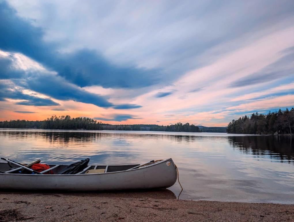a boat sitting on the shore of a lake at Acadia Sunset Fishing Cabin #1 family beach 1 dog in Sullivan