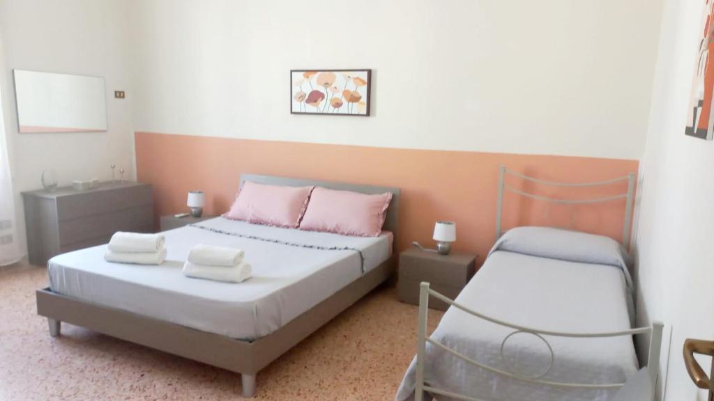 a bedroom with a bed with pink pillows and a chair at appartamento a due passi dal mare in San Vito lo Capo