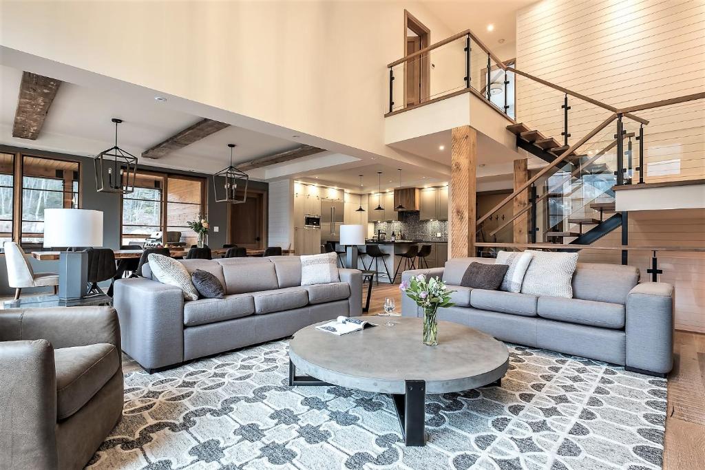 a living room with couches and a table at Havre 117 Tremblant Luxurious & Modern Ski-in Ski-out in Mont-Tremblant