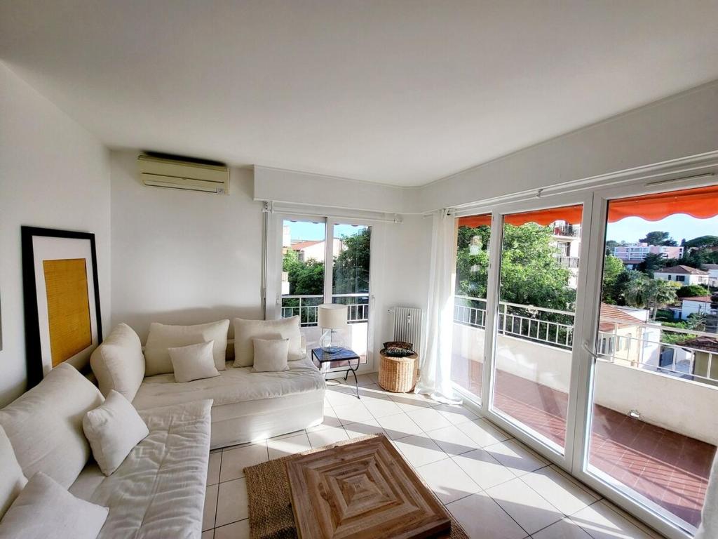 un salon avec un canapé et une grande fenêtre dans l'établissement Center of Antibes, Les Amaryllis - 3 Rooms, 5 minutes from the beaches, à Antibes