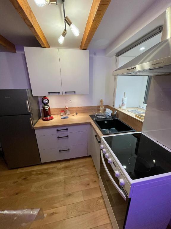 une cuisine avec des armoires blanches et un four à plaques de cuisson dans l'établissement Maison côté Auvergne, à Beauzac