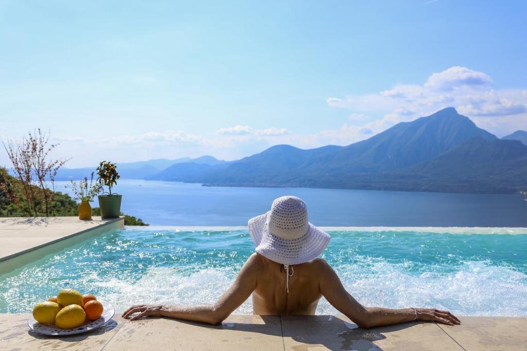 ein Mann mit Hut sitzt neben einem Swimmingpool in der Unterkunft Podere Sabaina, Private Villa mit Pool, Seeblick und 3 Wohneinheiten zur Alleinnutzung in Torri del Benaco