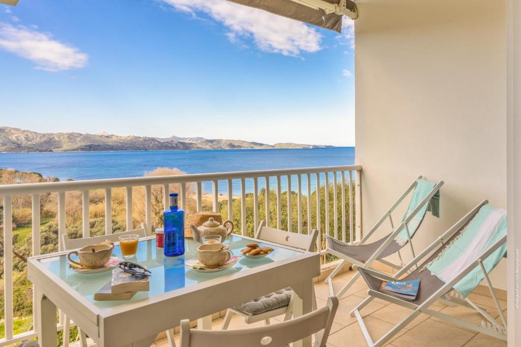 une table et des chaises sur un balcon avec vue sur l'océan dans l'établissement Les Marines T3 vue mer St-Florent, à Saint-Florent