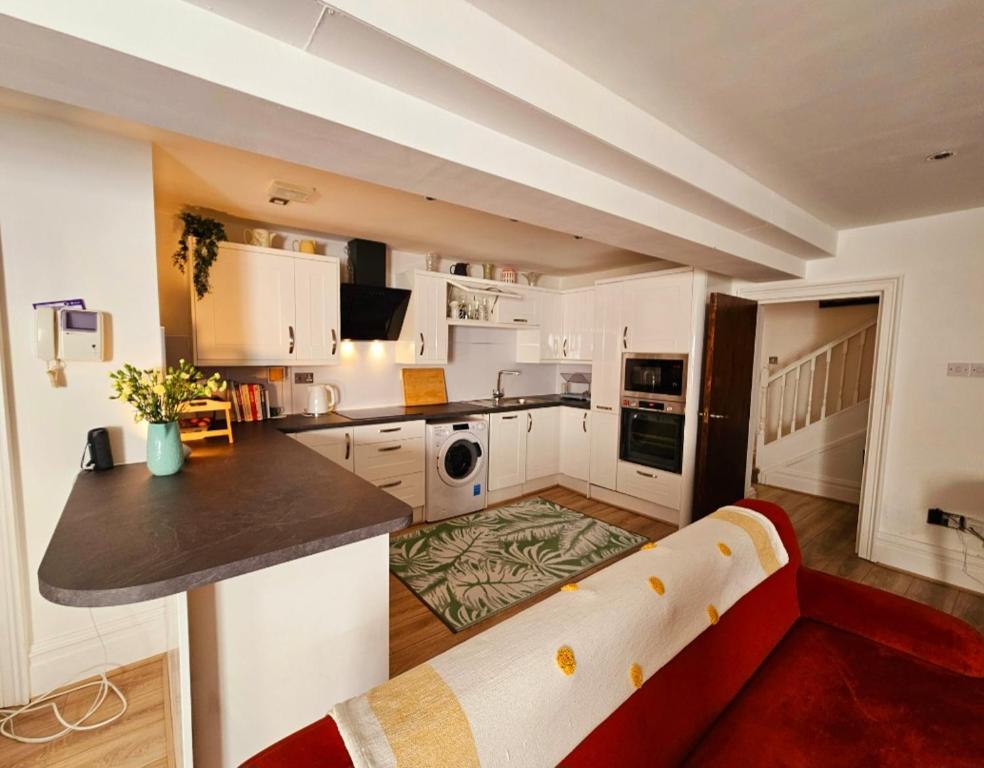 リバプールにあるLiverpool Georgian Quarter Apartmentの白いキャビネットと赤いソファ付きのキッチン