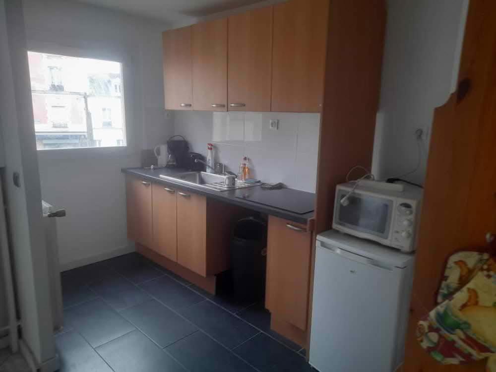 une petite cuisine avec un évier et un micro-ondes dans l'établissement Appartement calme & proche Paris, à Bois-Colombes