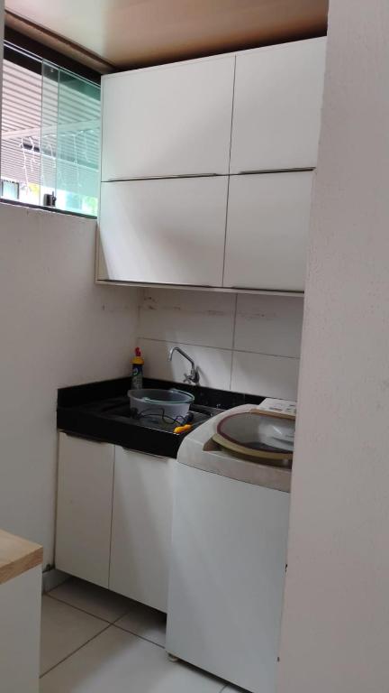 a kitchen with white cabinets and a sink at Complete beach house! in Cabedelo