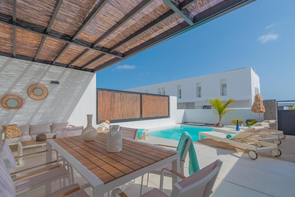 a patio with a table and chairs and a swimming pool at Villa Serena Blanca by Villalia Luxury Oasis & Private Pool in Playa Blanca