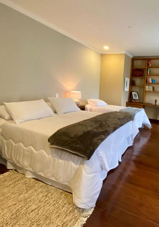 a bedroom with two beds and a book shelf at Espaço Tramonto in Itaipava