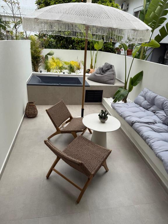 a patio with a table and chairs and an umbrella at erasmia luxury suite in Georgioupolis