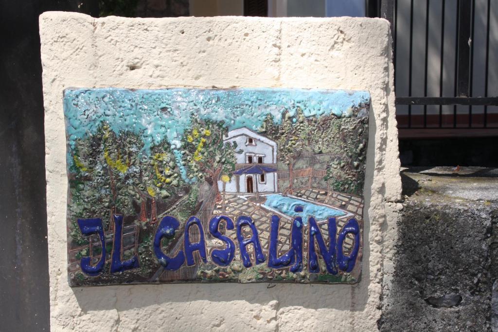 un cartello su un muro con un dipinto di una casa di Il Casalino a Maratea
