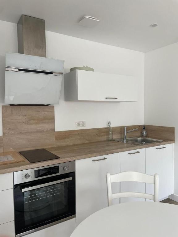 une cuisine blanche avec un évier et une cuisinière dans l'établissement Studio Bayonne Arènes Vacances, à Bayonne