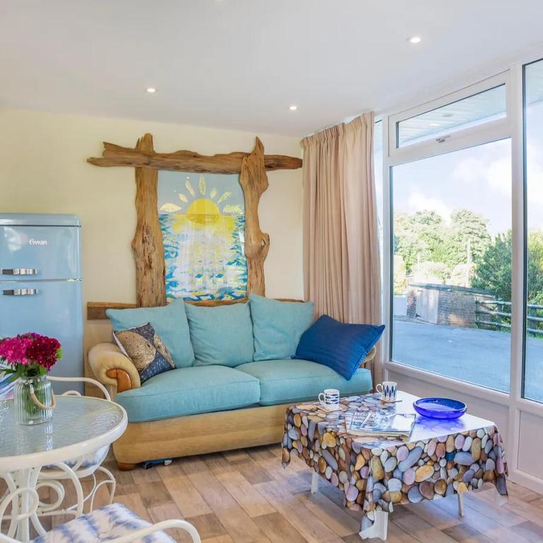 a living room with a blue couch and a table at Sea Moss Cabin in Tywyn