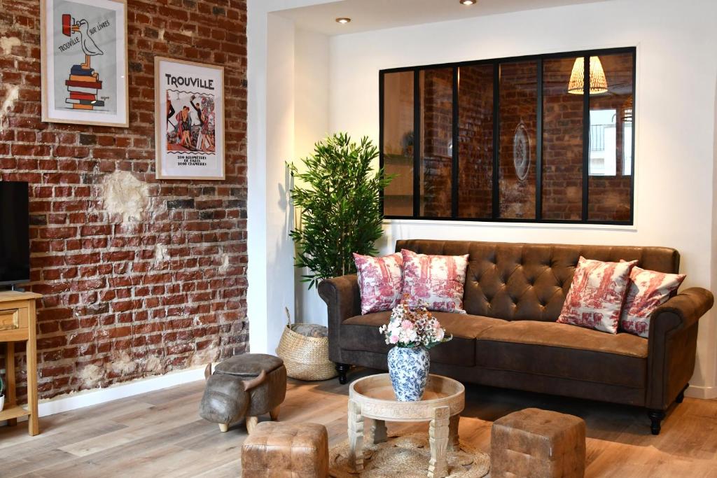 a living room with a couch and a brick wall at La belle échappée in Trouville-sur-Mer