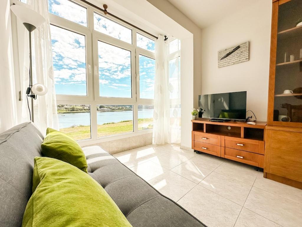 a living room with a couch and a large window at Apartamento Saica by ALÔGA in Corcubión