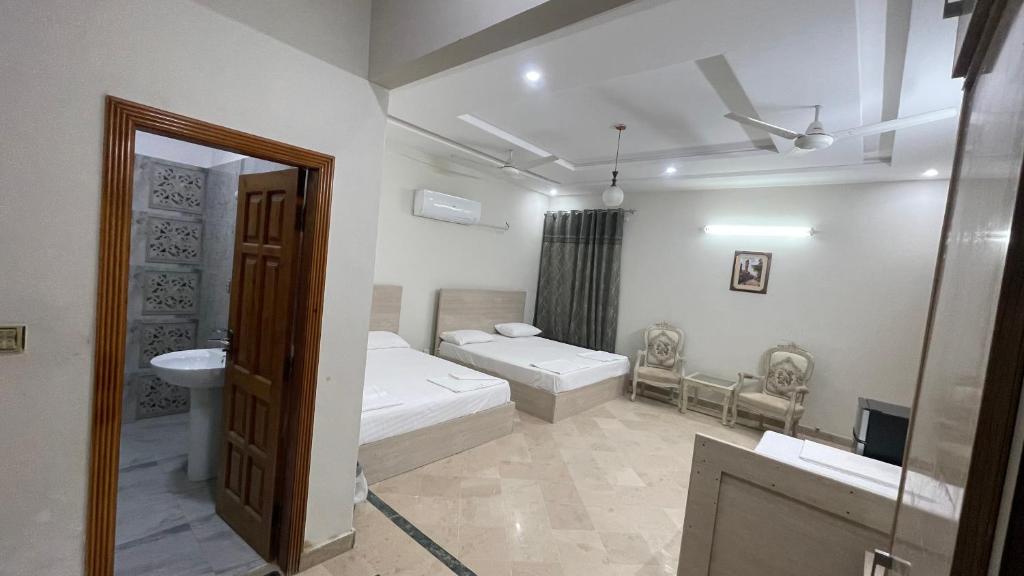 een badkamer met 2 bedden, een wastafel en een spiegel bij Midways Guest House and Hotels in Islamabad
