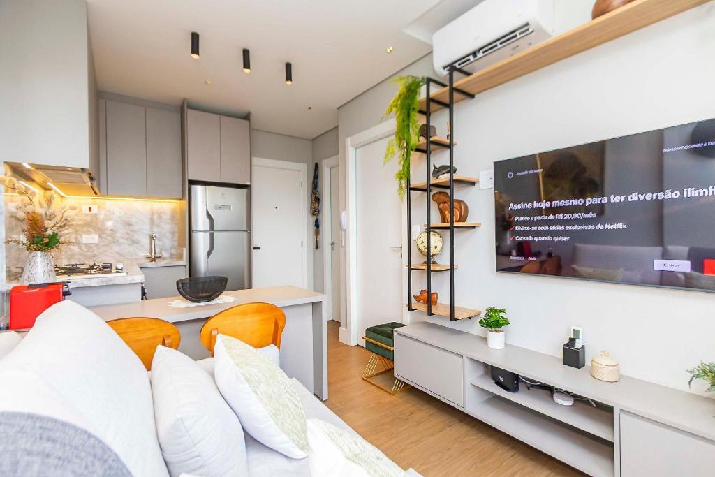 a kitchen and living room with a couch and a tv at Apartamento Premium c/vaga em Região Nobre-TEM0808 in Curitiba
