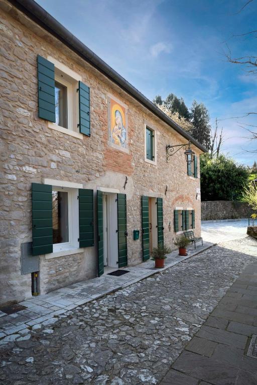 a brick building with green shutters on it at Ca' del Maglio in Cison di Valmarino