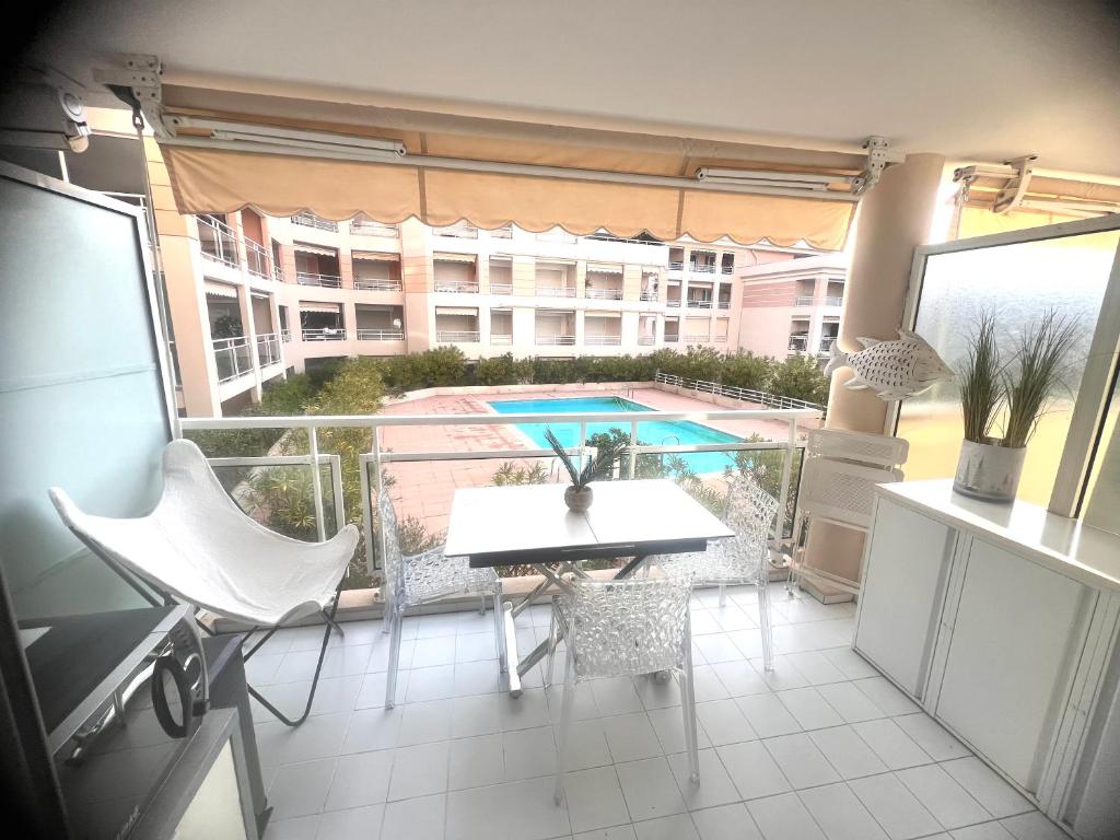 d'un balcon avec une table, des chaises et une piscine. dans l'établissement Port Azur Studio cabine 4 P - Pool beach Golfe Juan 5 min Cannes, à Vallauris