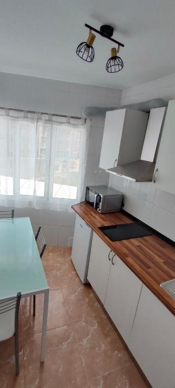 a kitchen with white cabinets and a table in it at Alojamiento céntrico Ribeira con parking sin ascensor in Ribeira