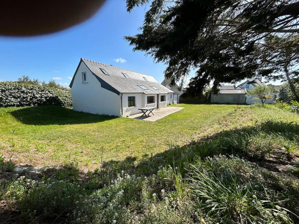 une petite maison blanche sur un champ herbeux dans l'établissement La Maison du Ruguel , Les Pieds dans l'Eau, à Roscoff