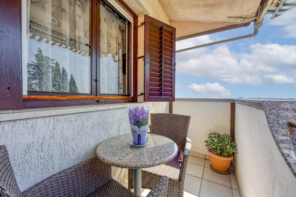 a table with a vase of flowers on a balcony at Mikelic Stara Barbariga in Barbariga