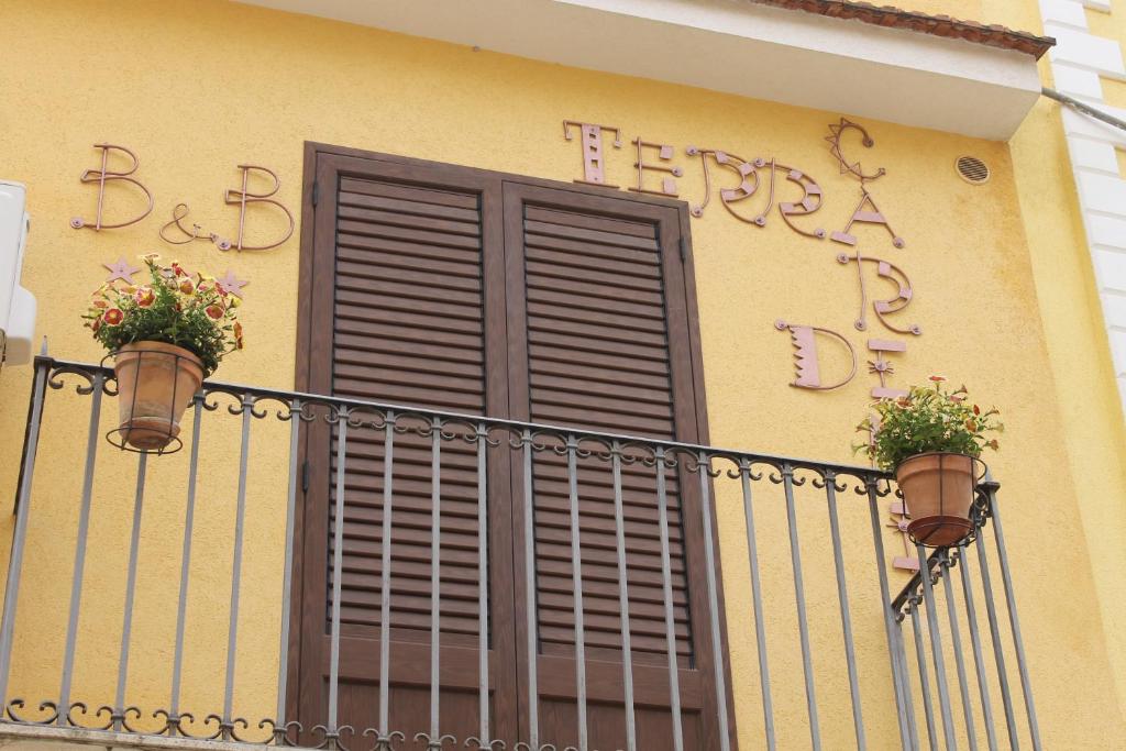 d'un balcon avec une fenêtre et deux plantes en pot. dans l'établissement Terra di Carini, à Carini