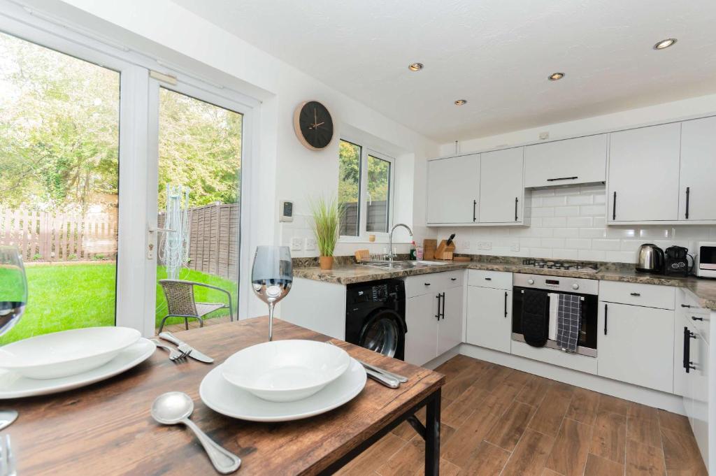 a kitchen with white cabinets and a wooden table at Modern 3 Bedroom Home in Swindon with Parking in Swindon