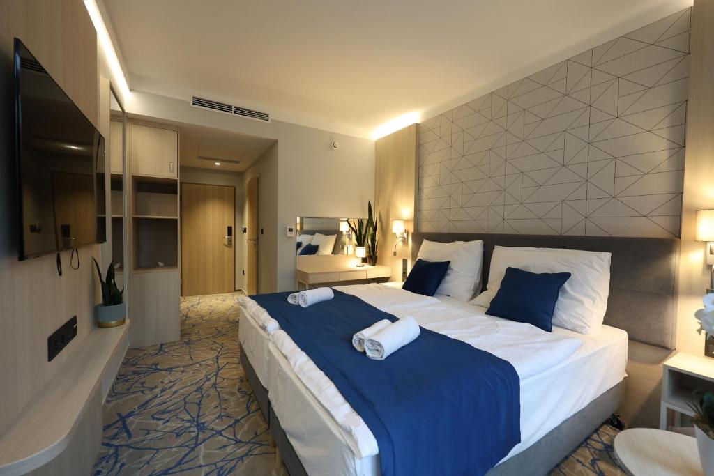 a large bedroom with a large bed with blue sheets at AquaMed Hotel Harkány in Harkány
