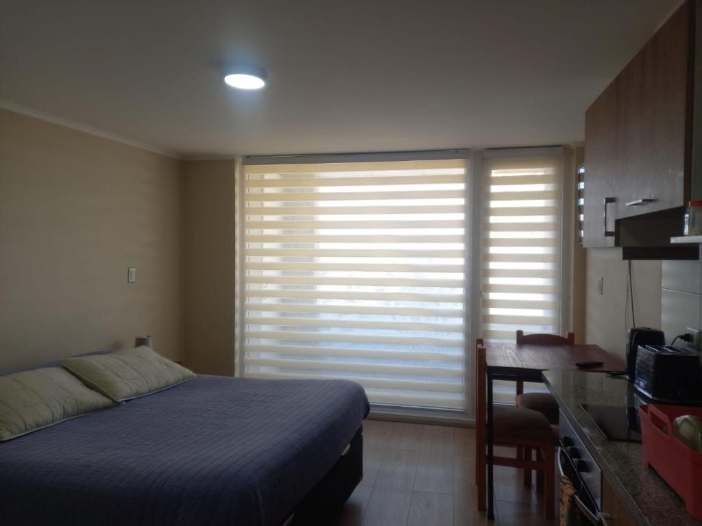 a bedroom with a bed and a desk and a window at Departamento Edificio Centro Osorno in Osorno