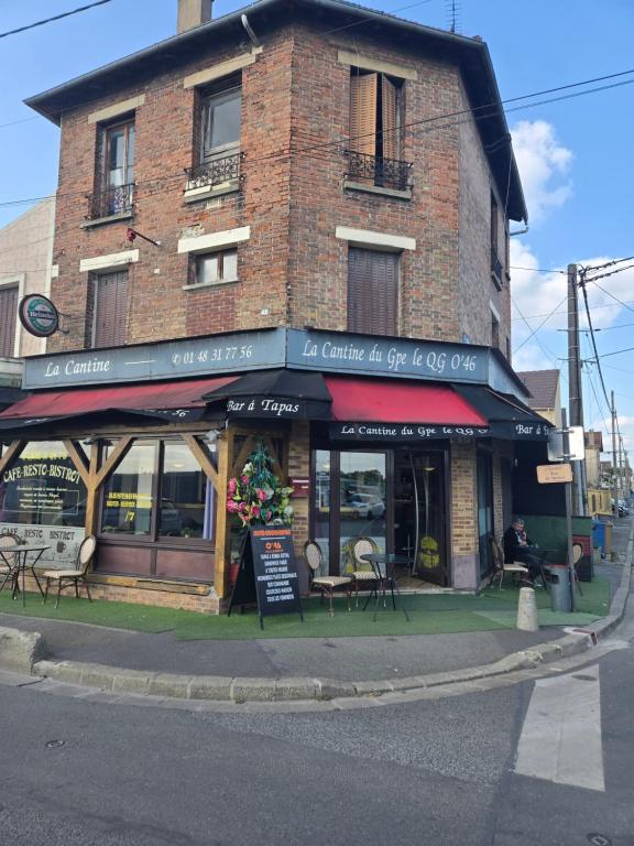 un bâtiment en briques avec des tables et des chaises devant lui dans l'établissement Couche-tard, au Bourget