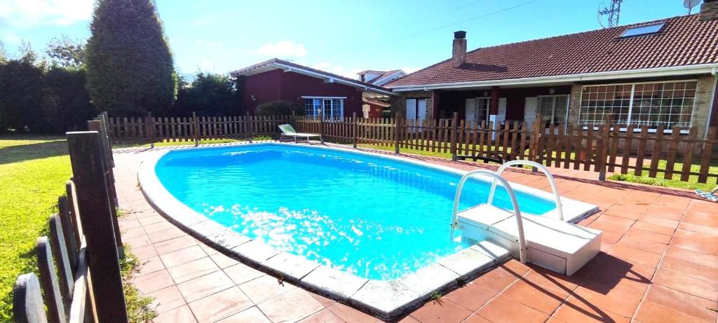 a swimming pool in a yard next to a house at Guirigay CASA CON PISCINA in Muros de Nalón