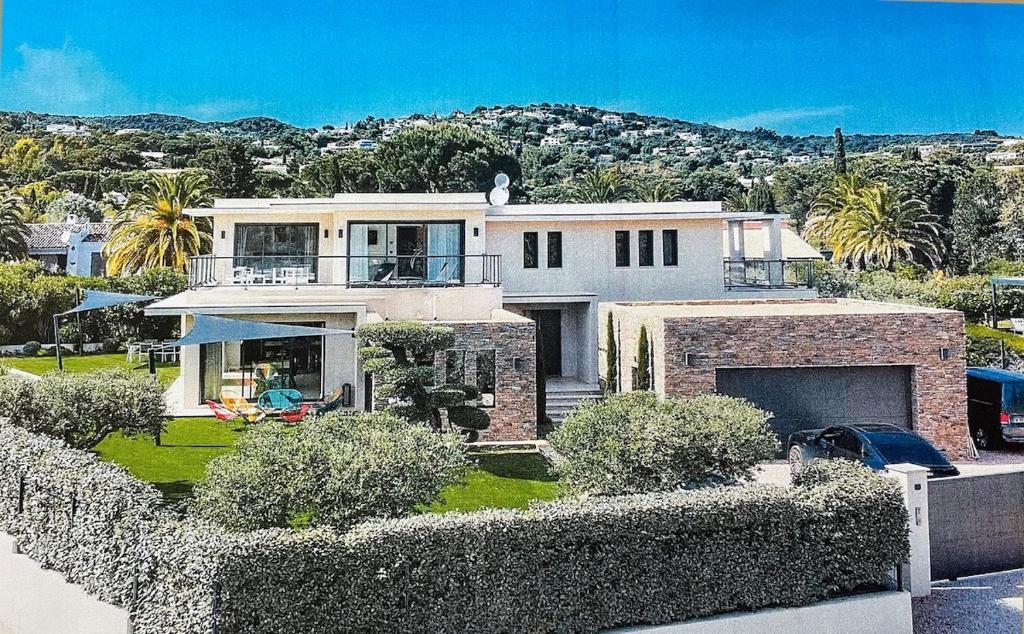 une grande maison blanche avec une clôture devant elle dans l'établissement Villa de luxe, piscine, plage 7mns, St Tropez 15km, à La Croix-Valmer