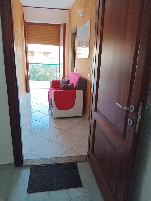 a living room with a red and white couch next to a door at Le Fontanelle Apartment in Siniscola