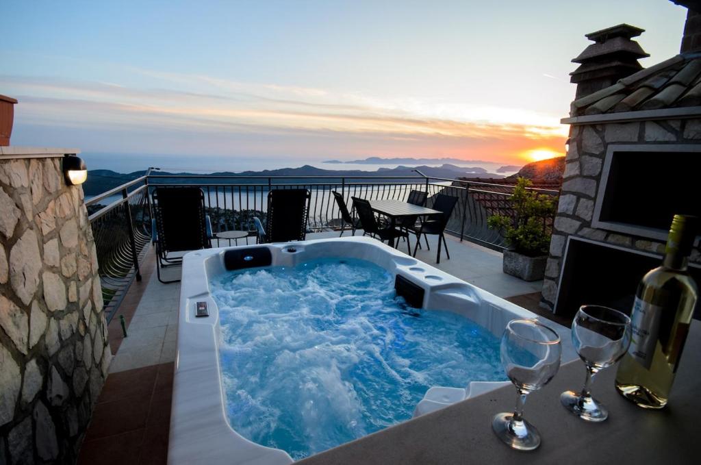 a hot tub on a balcony with wine glasses at Village house Kate Dubravica in Dubravica